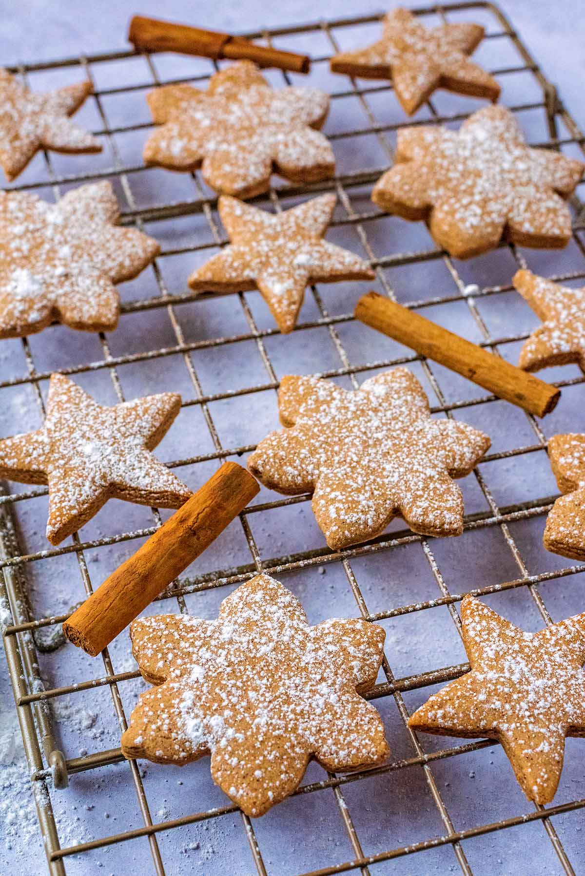 Star shaped biscuits on a cooling rack with cinnamon sticks.