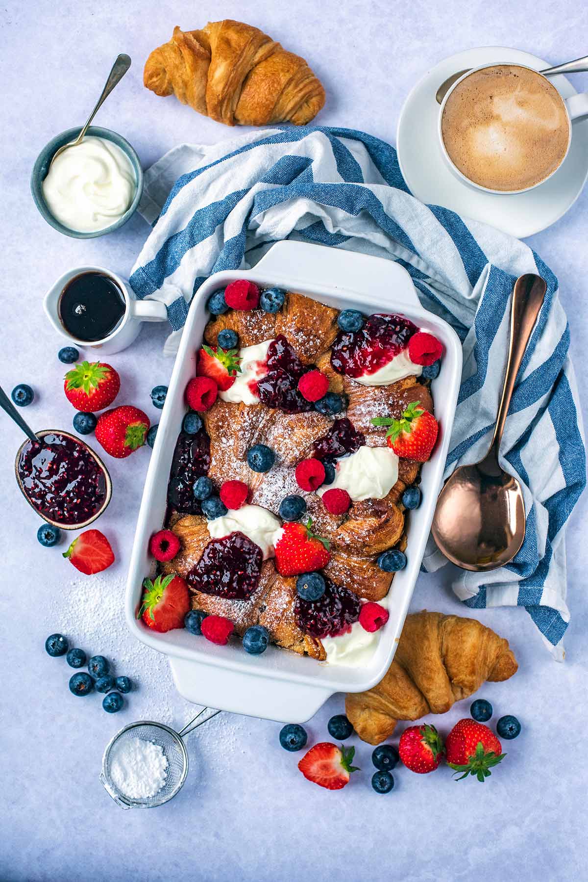 A baking dish contining bked croissants topped with yogurt and berries.