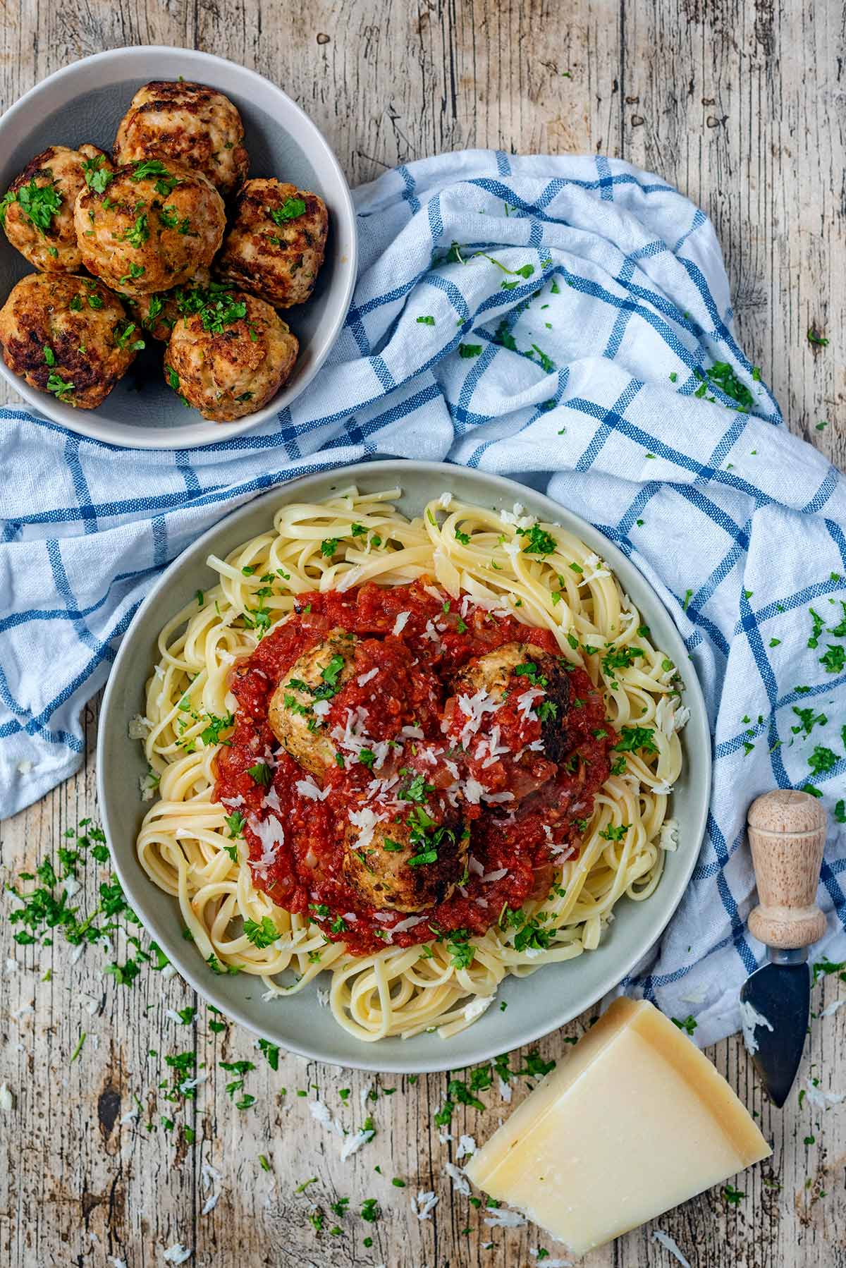 A bowl of spaghetti and meatballs in a tomato sauce next to a blue and white towel.