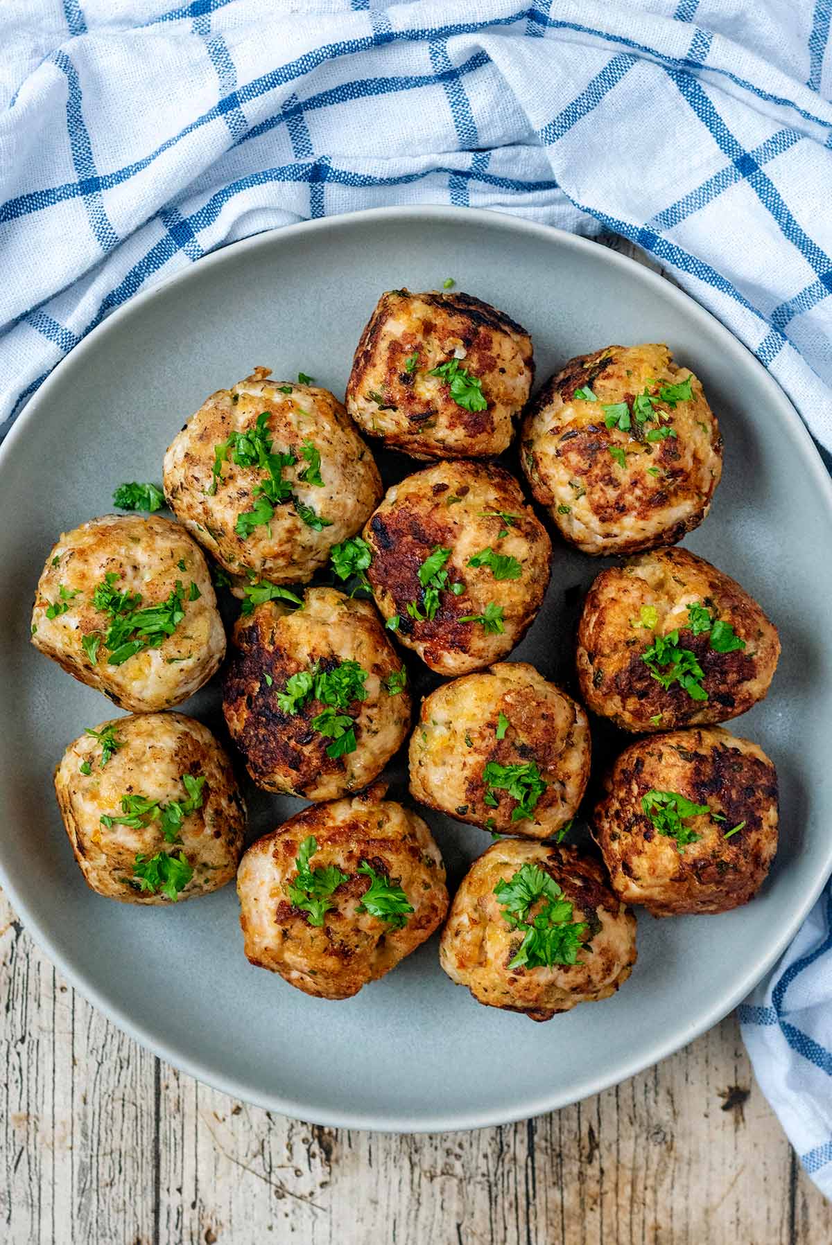 A plate of cooked meatballs with chopped herbs sprinkled over them.