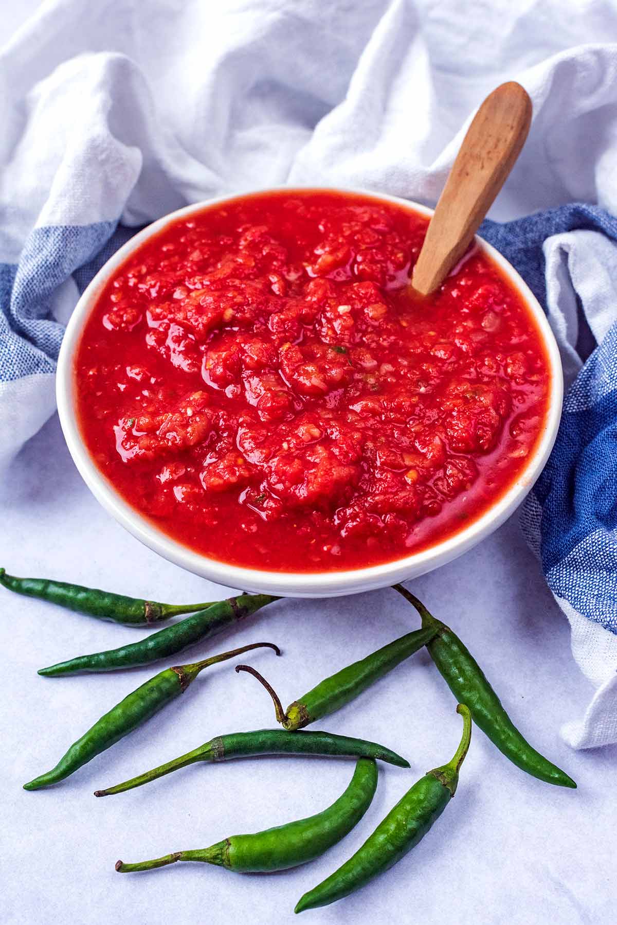 A bowl of chilli sauce with a spoon in it.