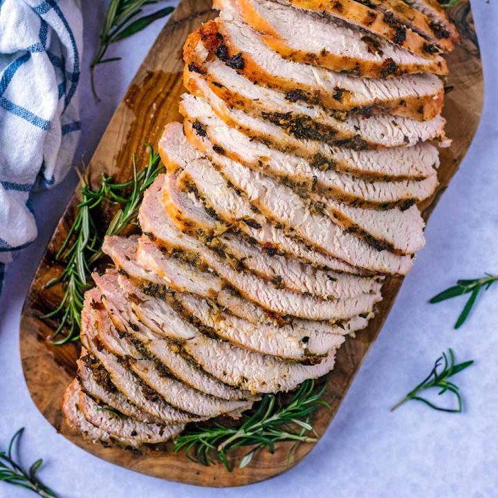 Roast turkey breast sliced up on a serving board.