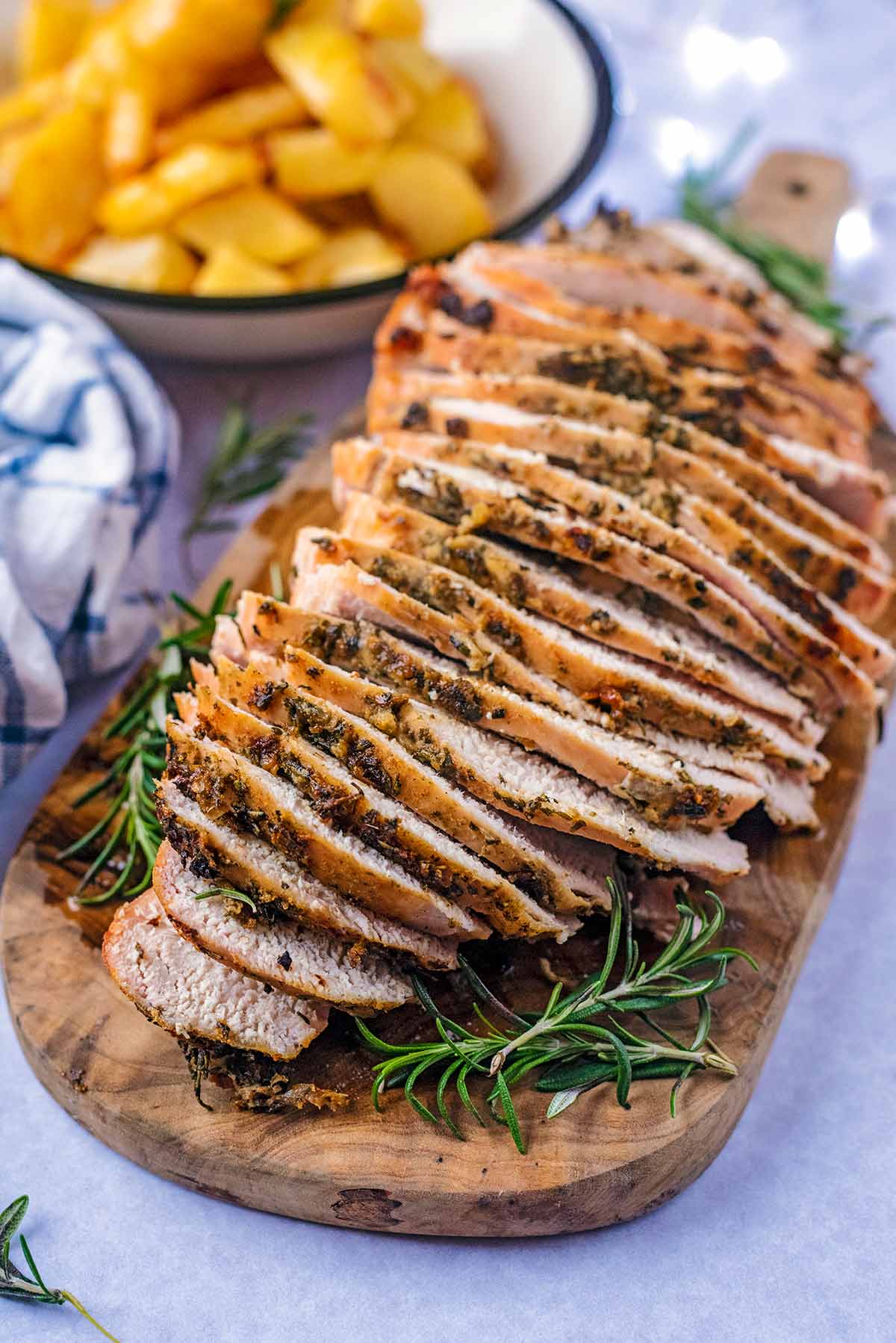 Thin slices of turkey on a wooden serving board.
