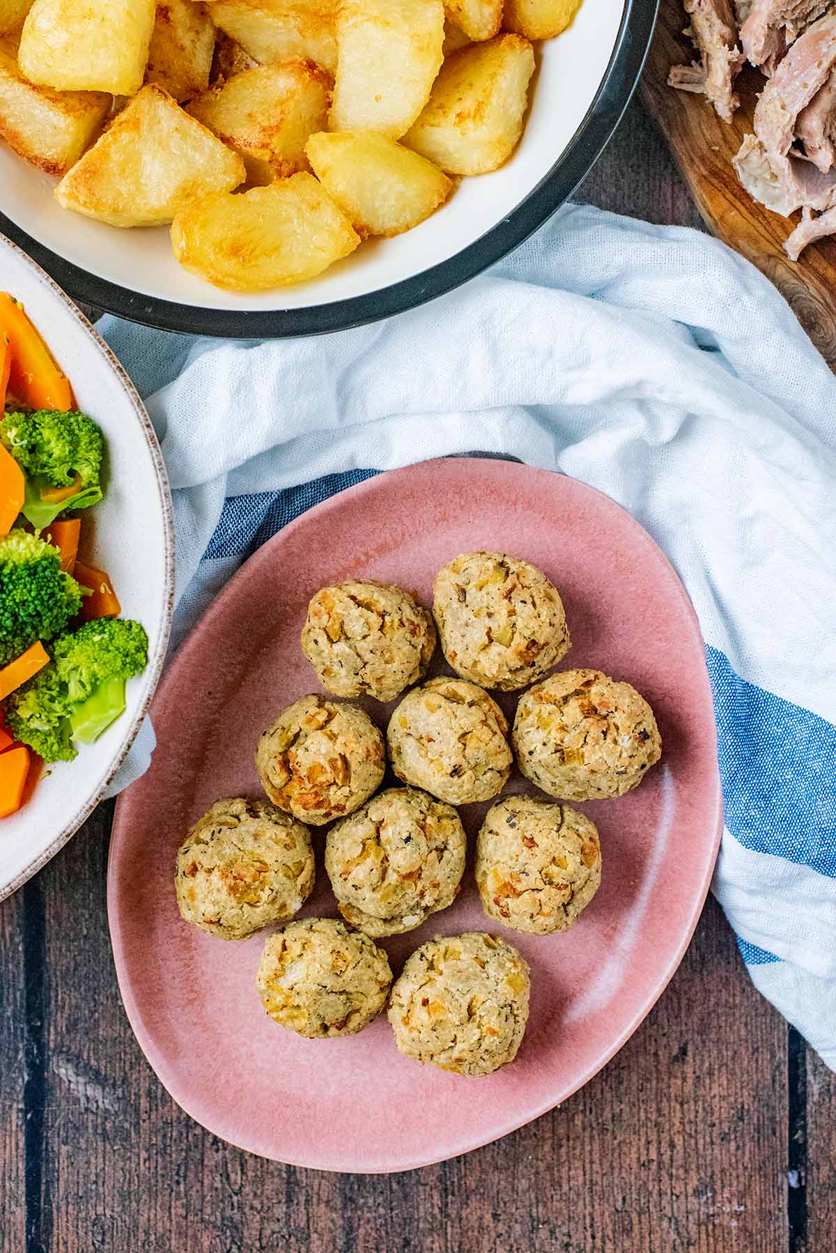 A plate of stuffing balls surrounded by cooked meat and vegetbles.