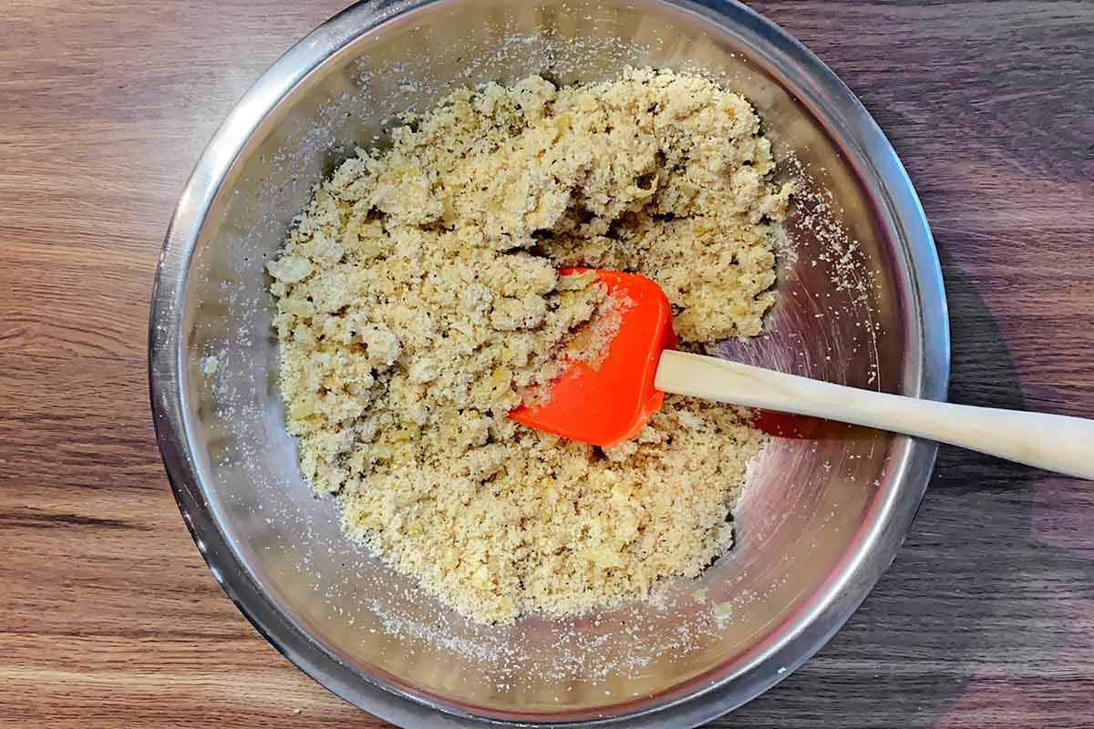 A spoon mixing the mixture into a crumbly consistency. 