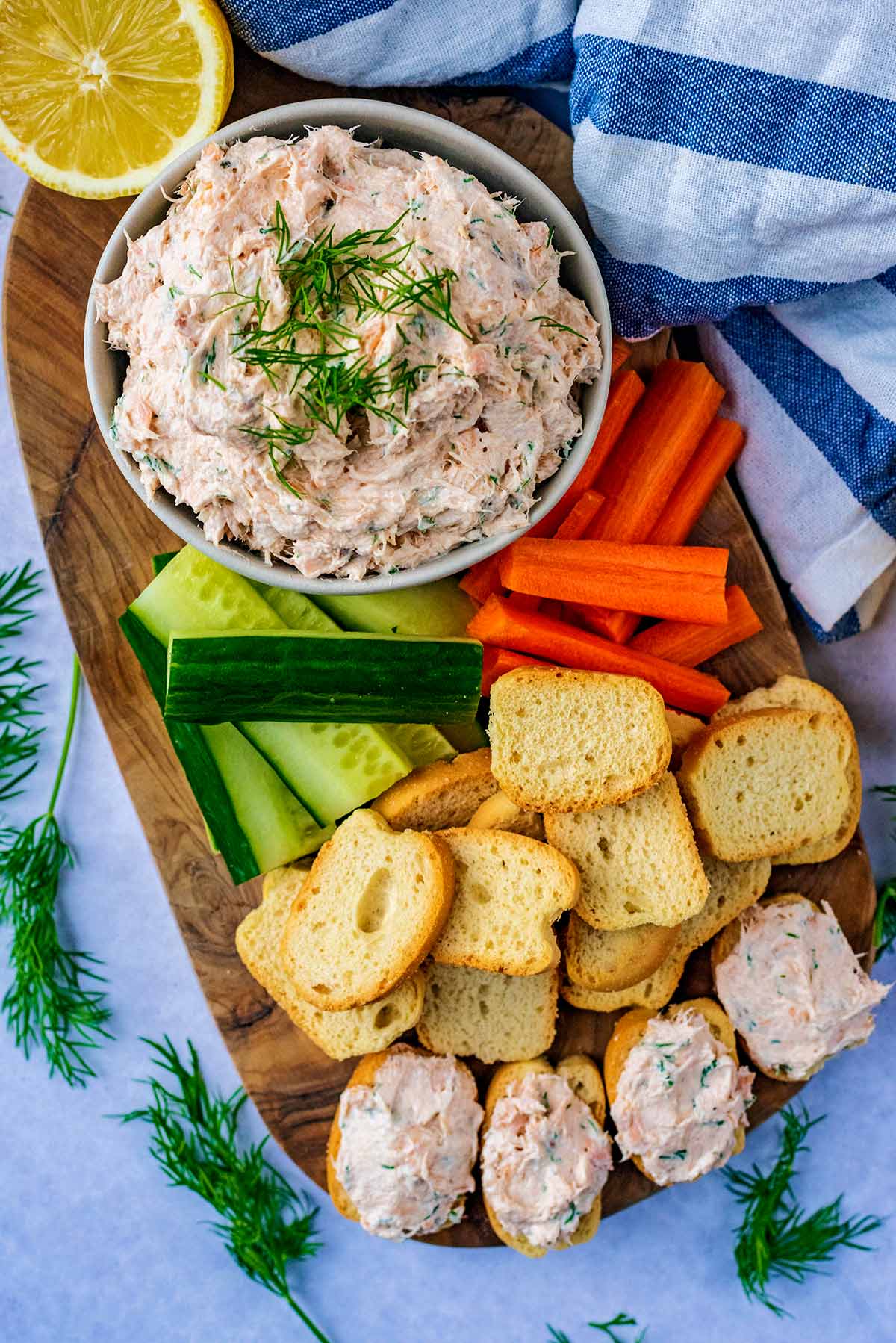 A bowl of salmon pate on a board with some crudites.