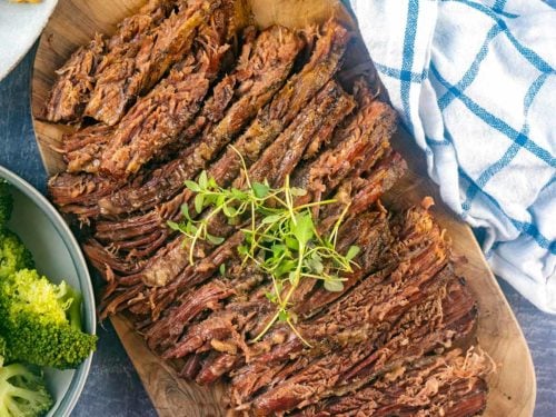 Slow cooker beef brisket sliced up on a serving board.
