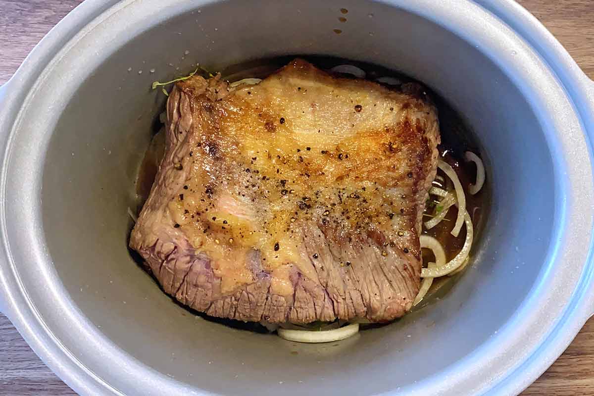 Browned brisket joint added to the slow cooker.