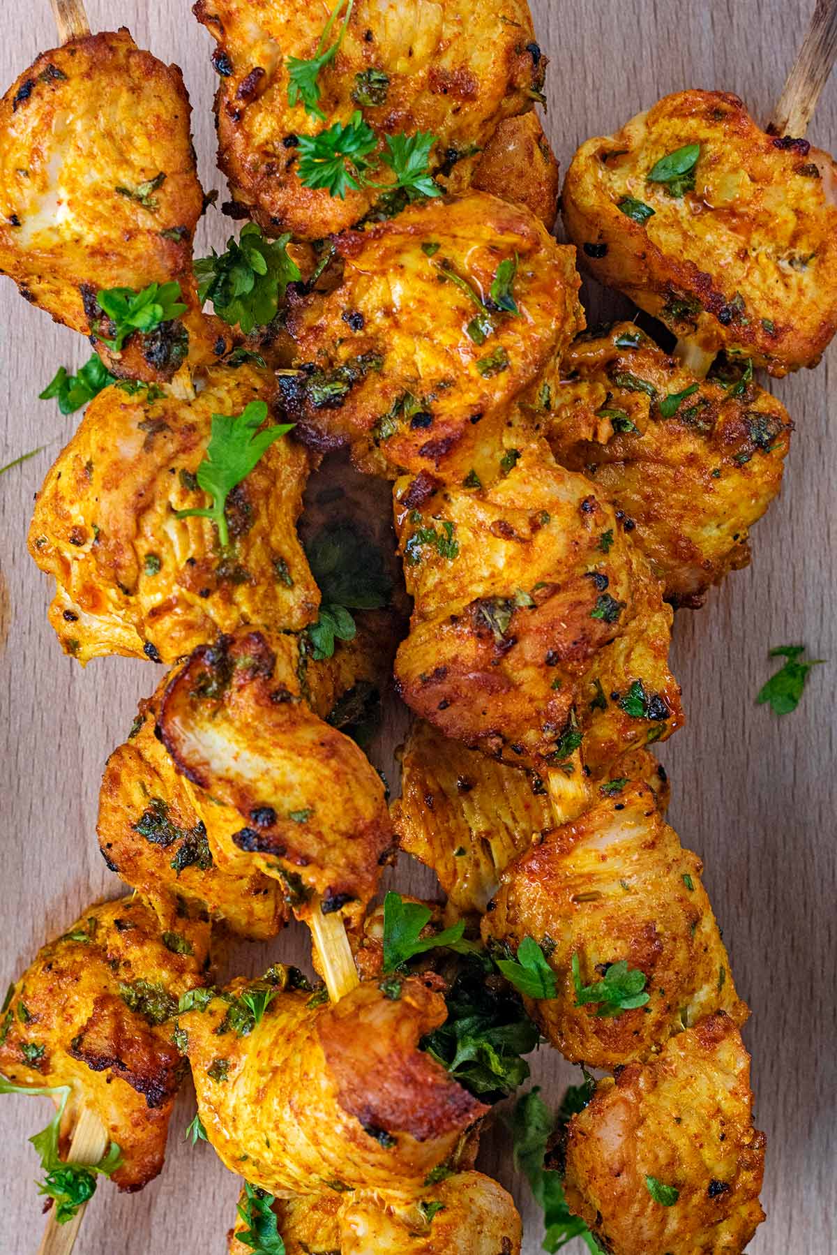 Cooked turkey chunks on skewers with chopped parsley sprinkled over them.