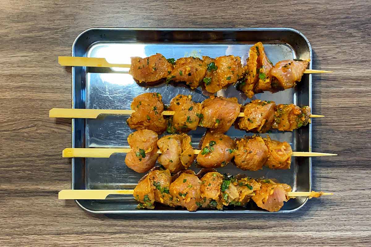 Four wooden skewers with marinated turkey on them.