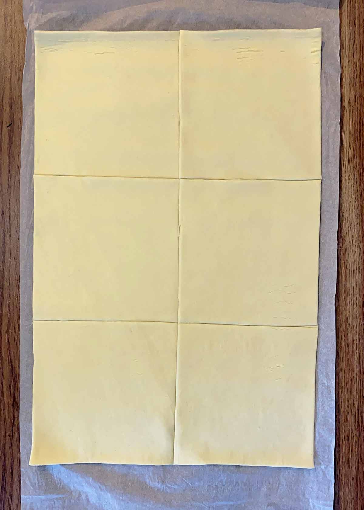 A sheet of uncooked puff pastry cut into six equal squared.