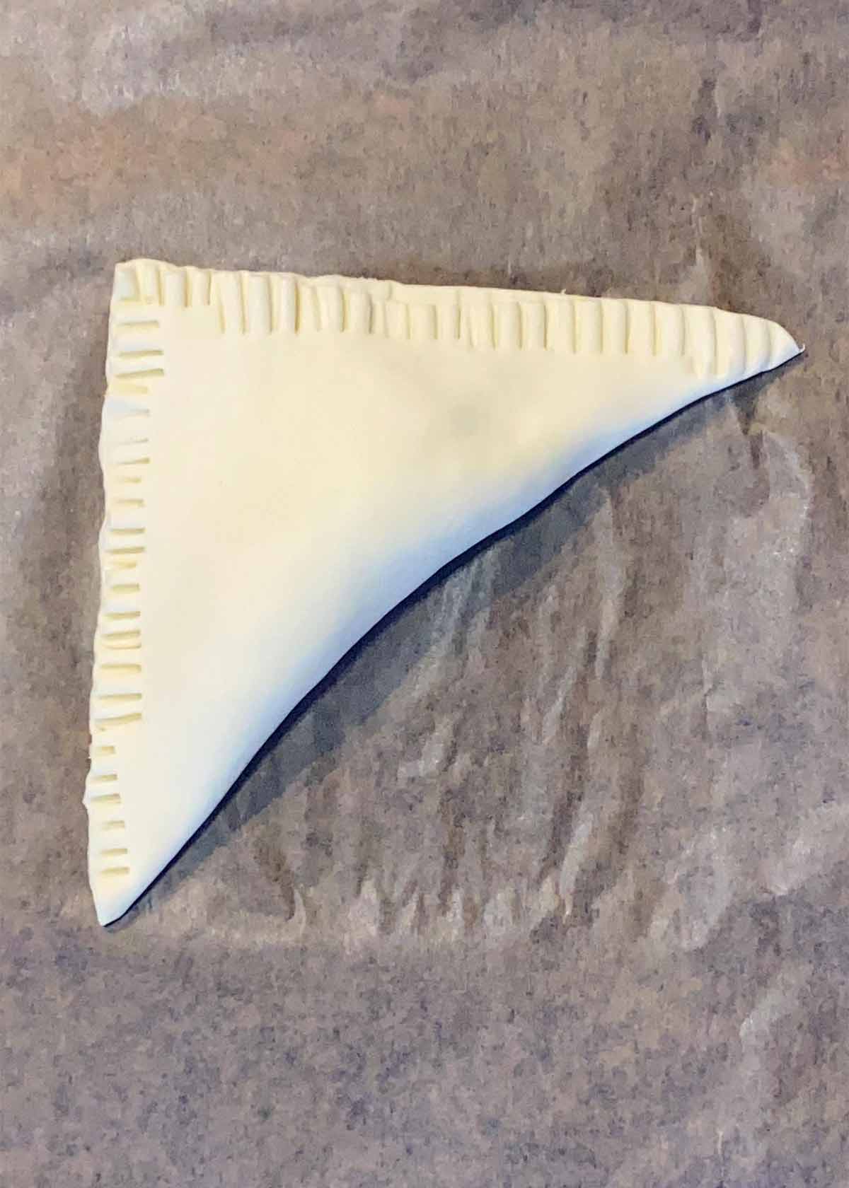 The pastry folded over the apples into a triangle and the edges crimped.