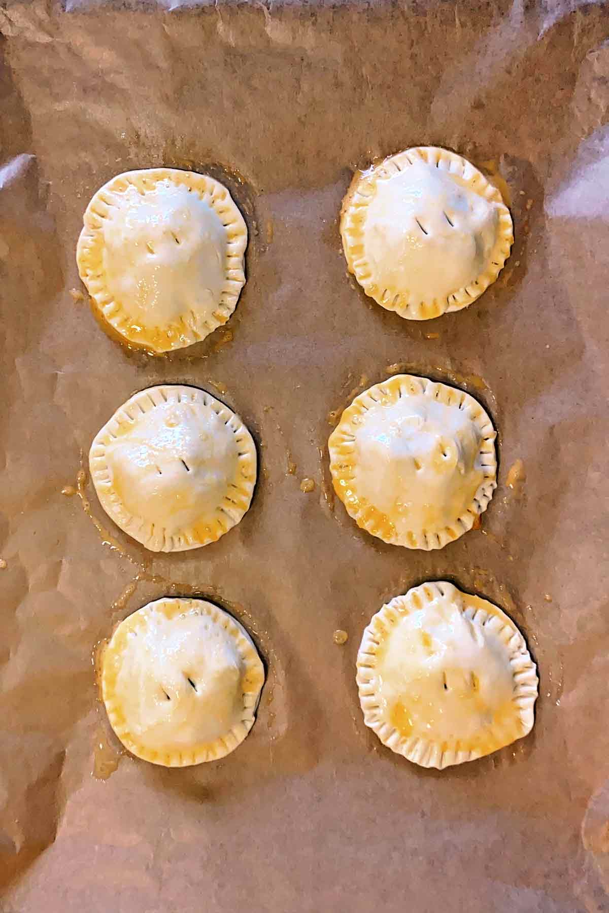 The pies brushed with egg and two holes cut in the top.