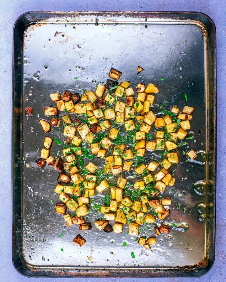 Roast swede on a baking tray with rosemary sprinkled over.