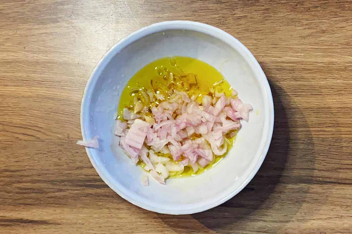 A small bowl containing chopped shallots, honey, mustard and lemon juice.