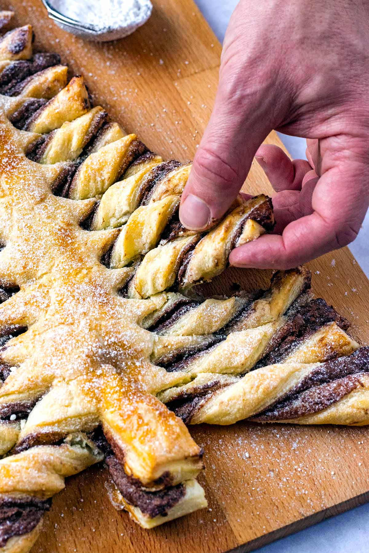 A hand pulling a branch from a pastry Christmas tree.
