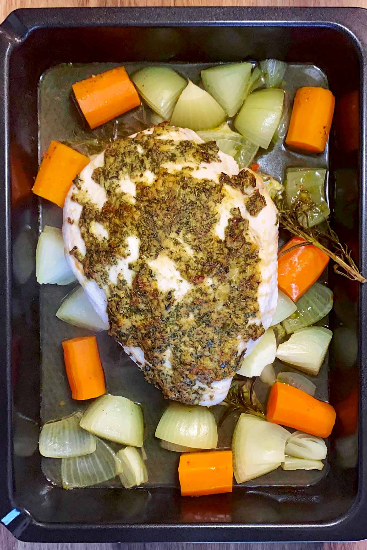 Part cooked turkey breast in a baking tray.