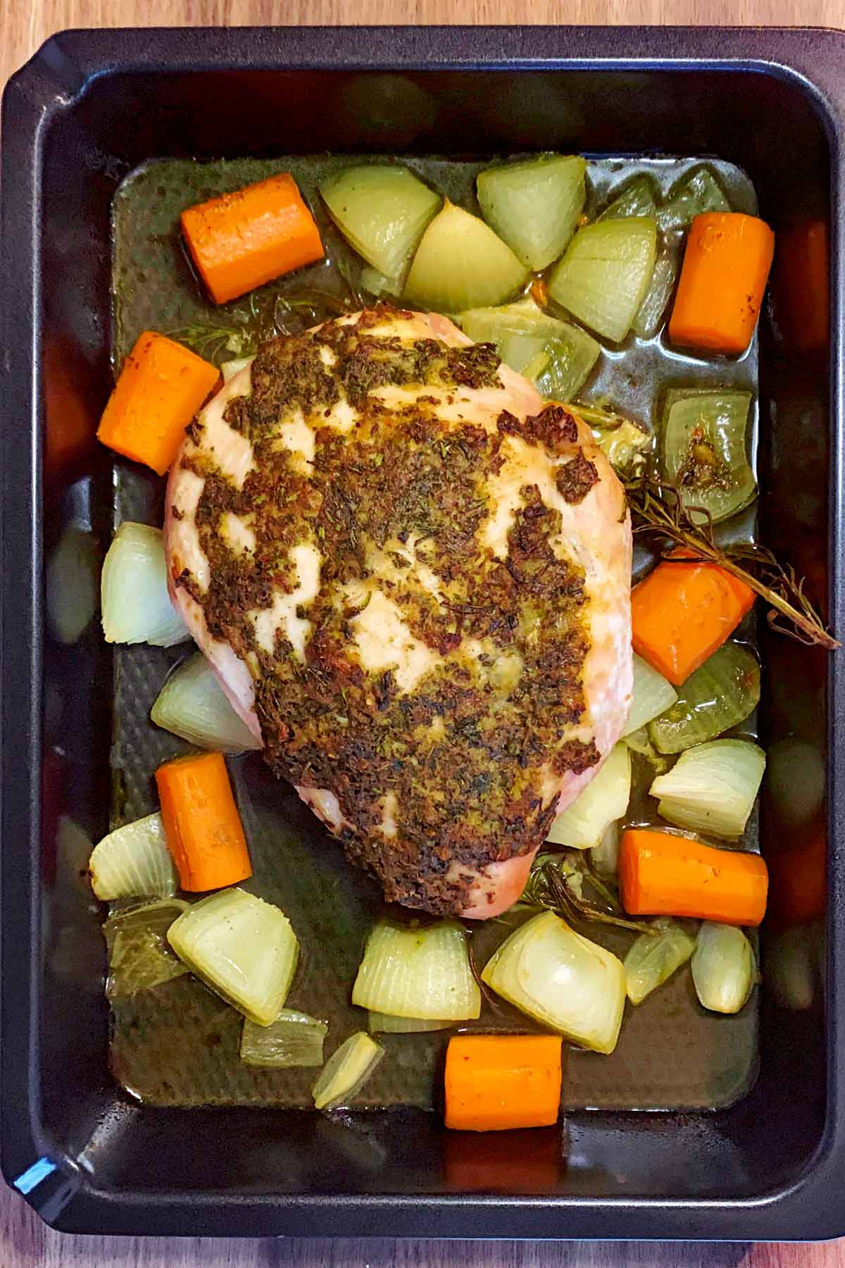 Cooked turkey breast in a baking tray with vegetables.