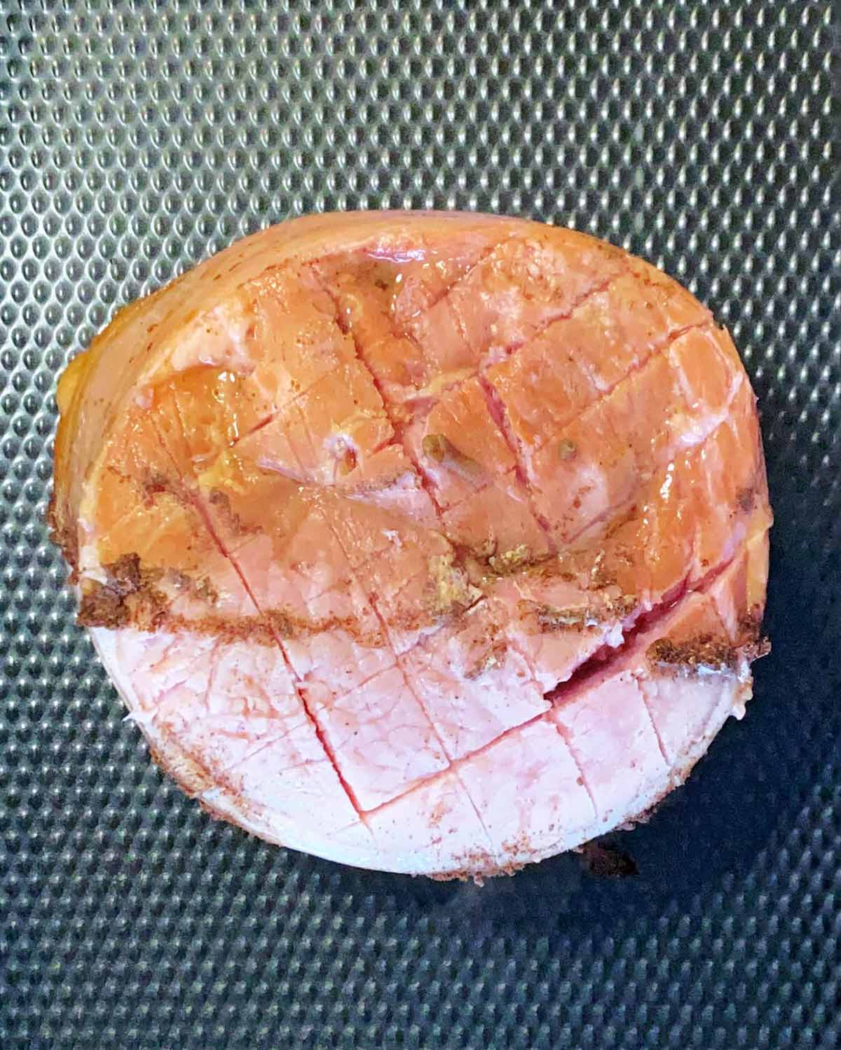 Cooked gammon with criss cross knife scores across it.