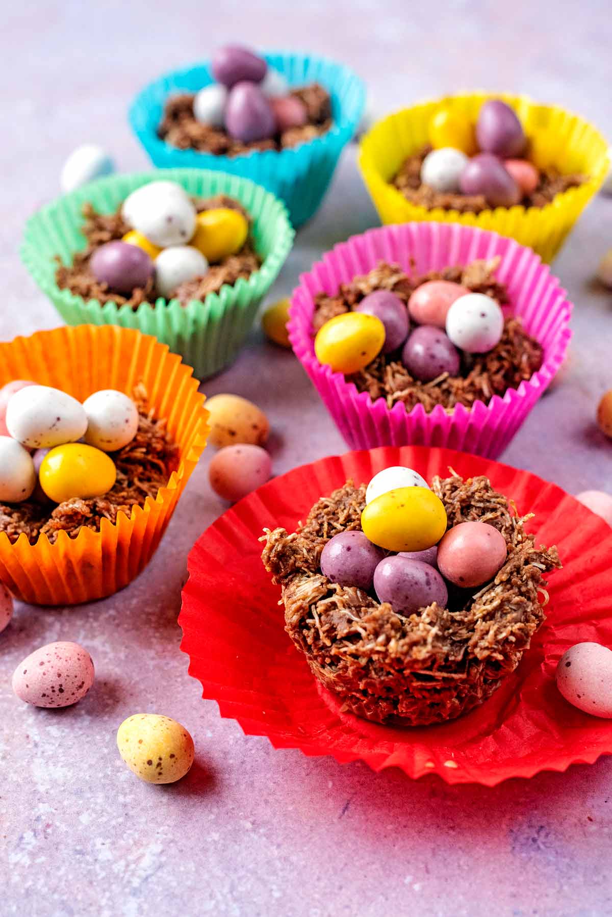 Six different coloured muffin cases each containing a chocolate nest.