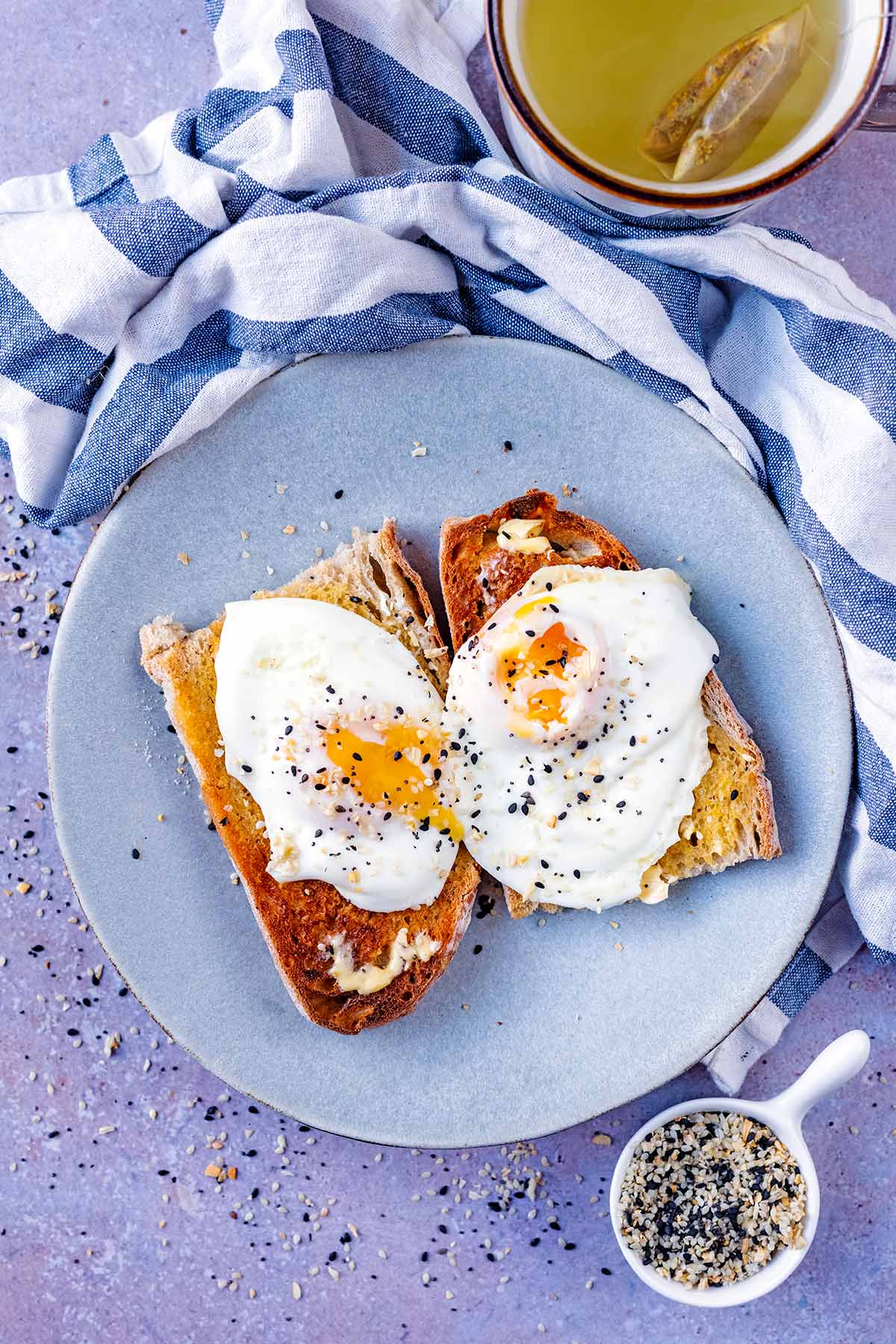 Two fried eggs on toast with broken yolks.