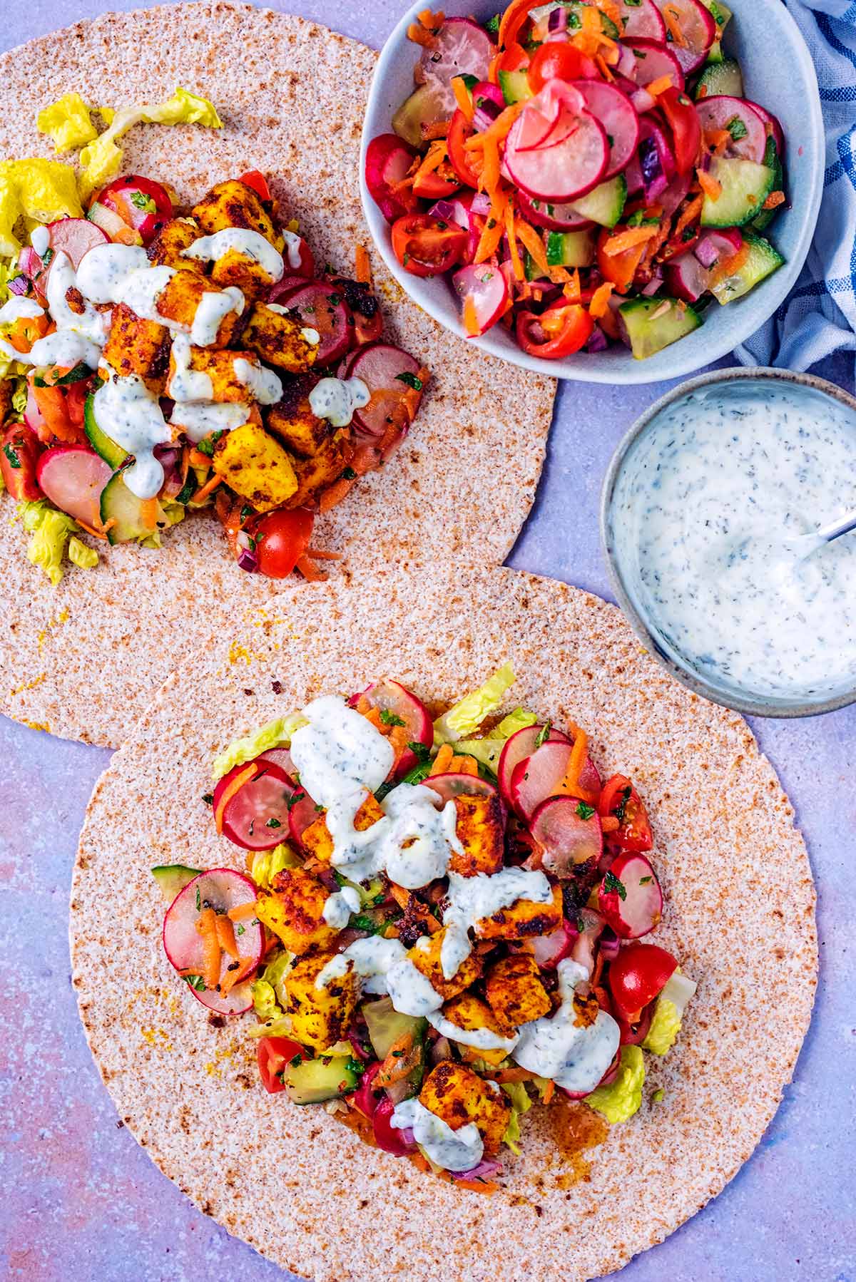 Two wraps topped with salad and cooked paneer.