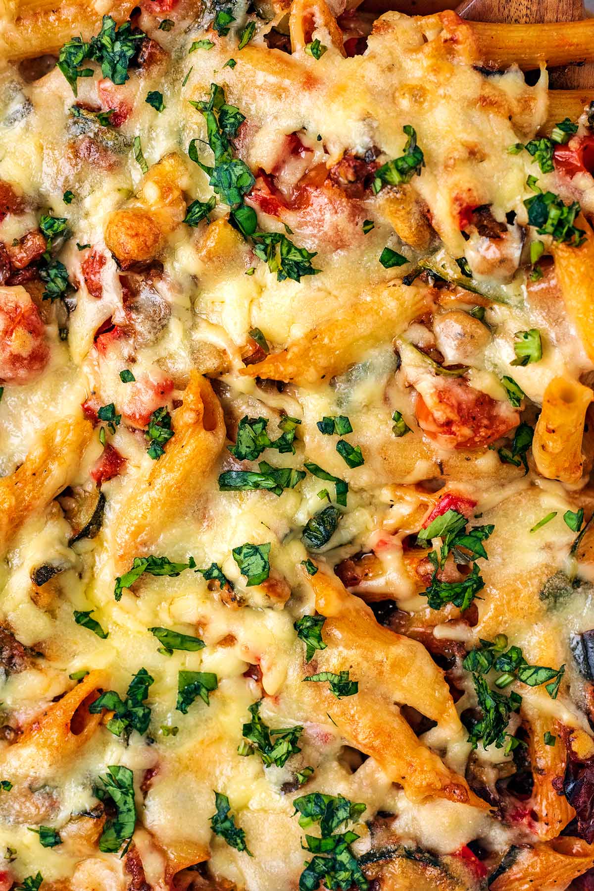 Chopped basil on top of a cheesy topped pasta bake.