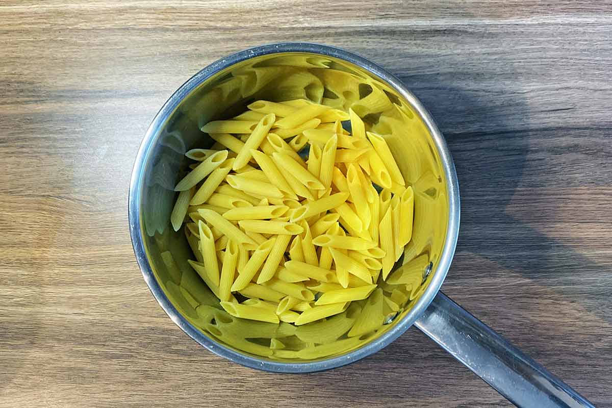 Uncooked penne pasta in a saucepan.