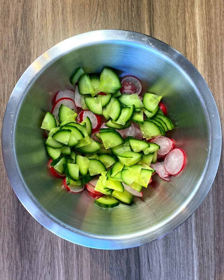 A bowl of sliced cucumber and sliced radish.