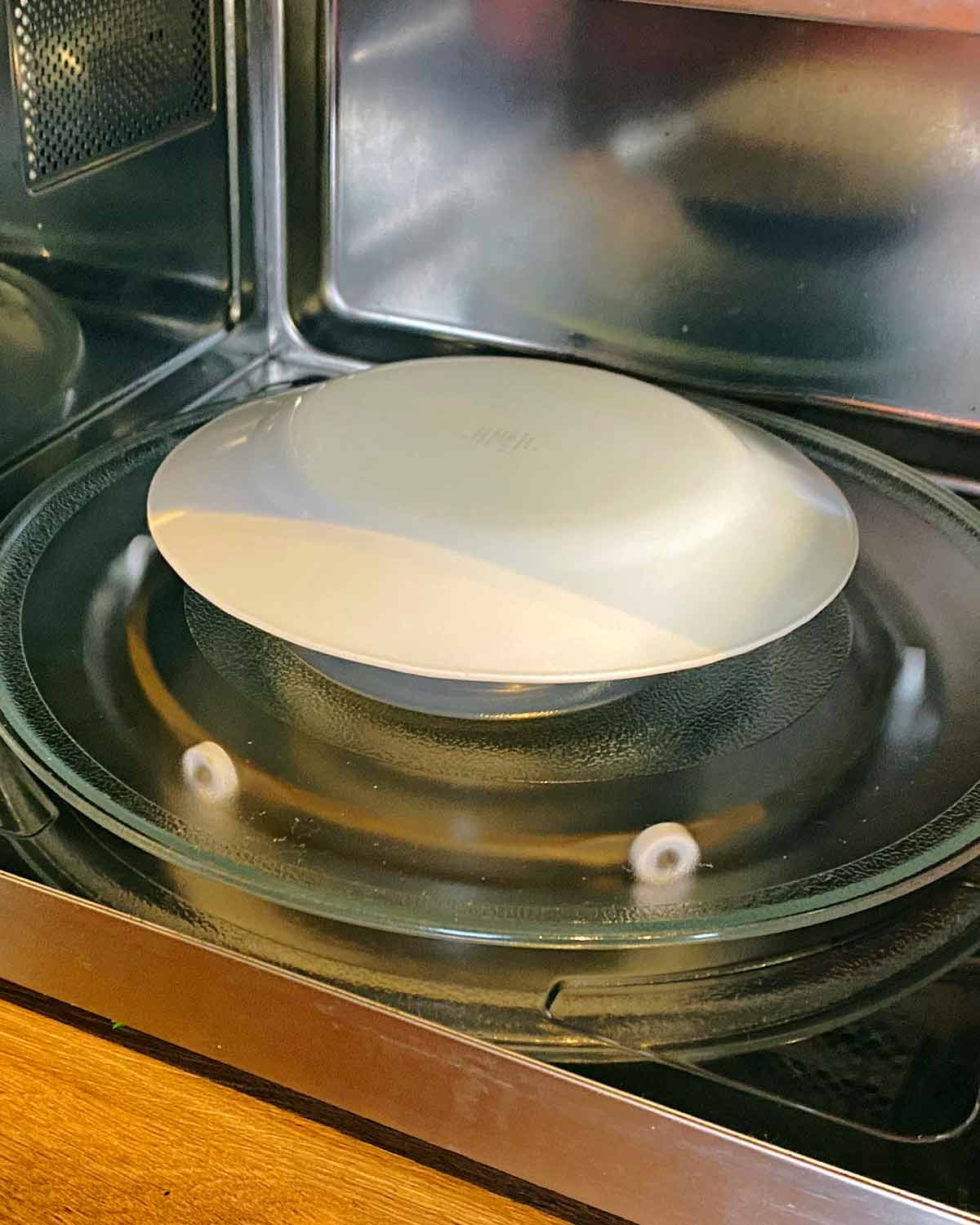 Interior of a microwave with a bowl covered with a plate.