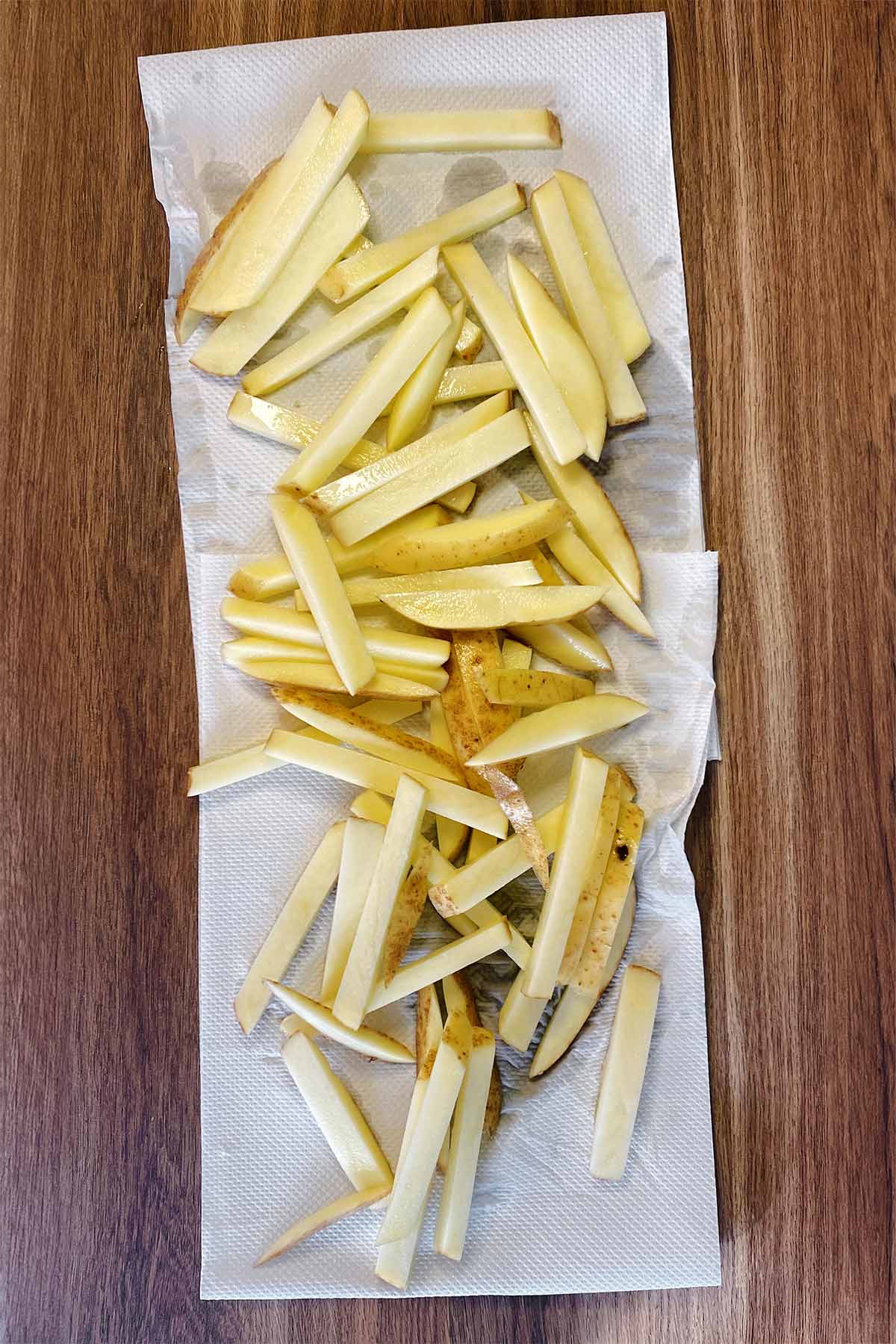 Uncooked potato chips on some paper towel.