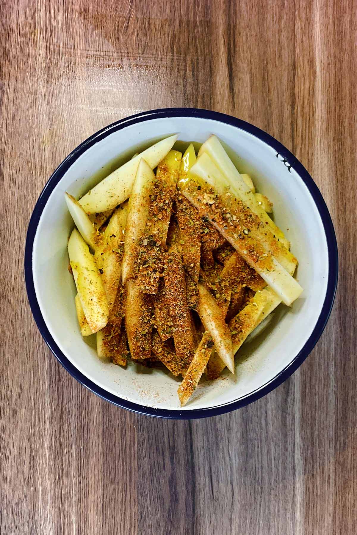 A bowl of uncooked chips in a bowl covered in seasoning.