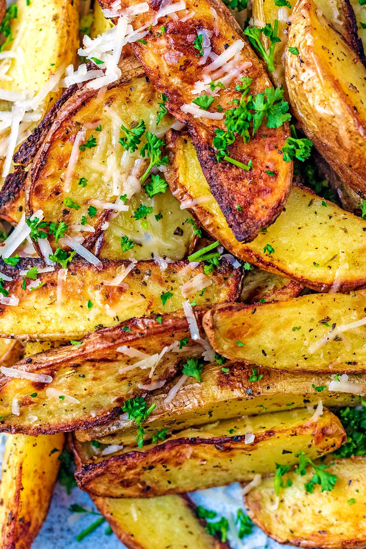 Cooked potato wedges topped with grated Parmesan and chopped parsley.