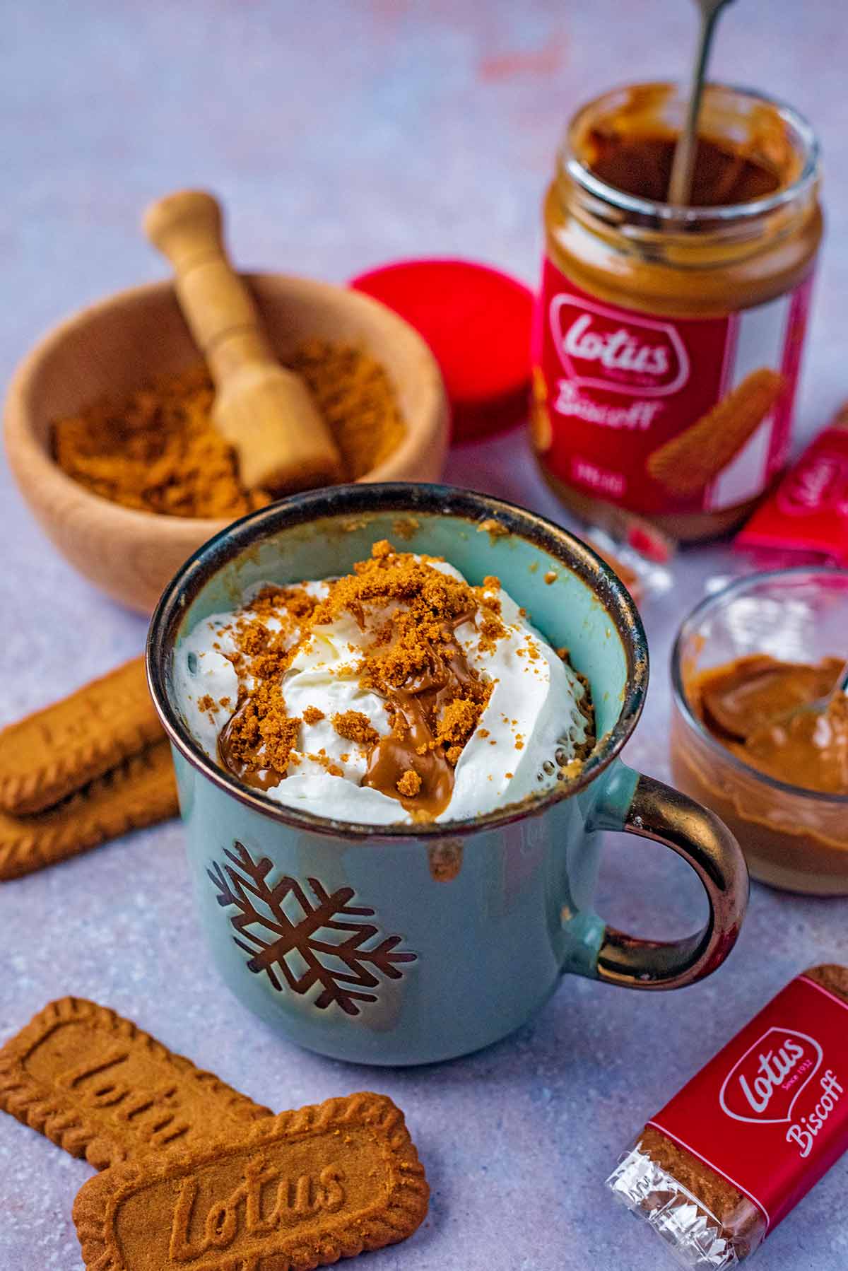A mug cake topped with whipped cream and crushed Biscoff biscuit.