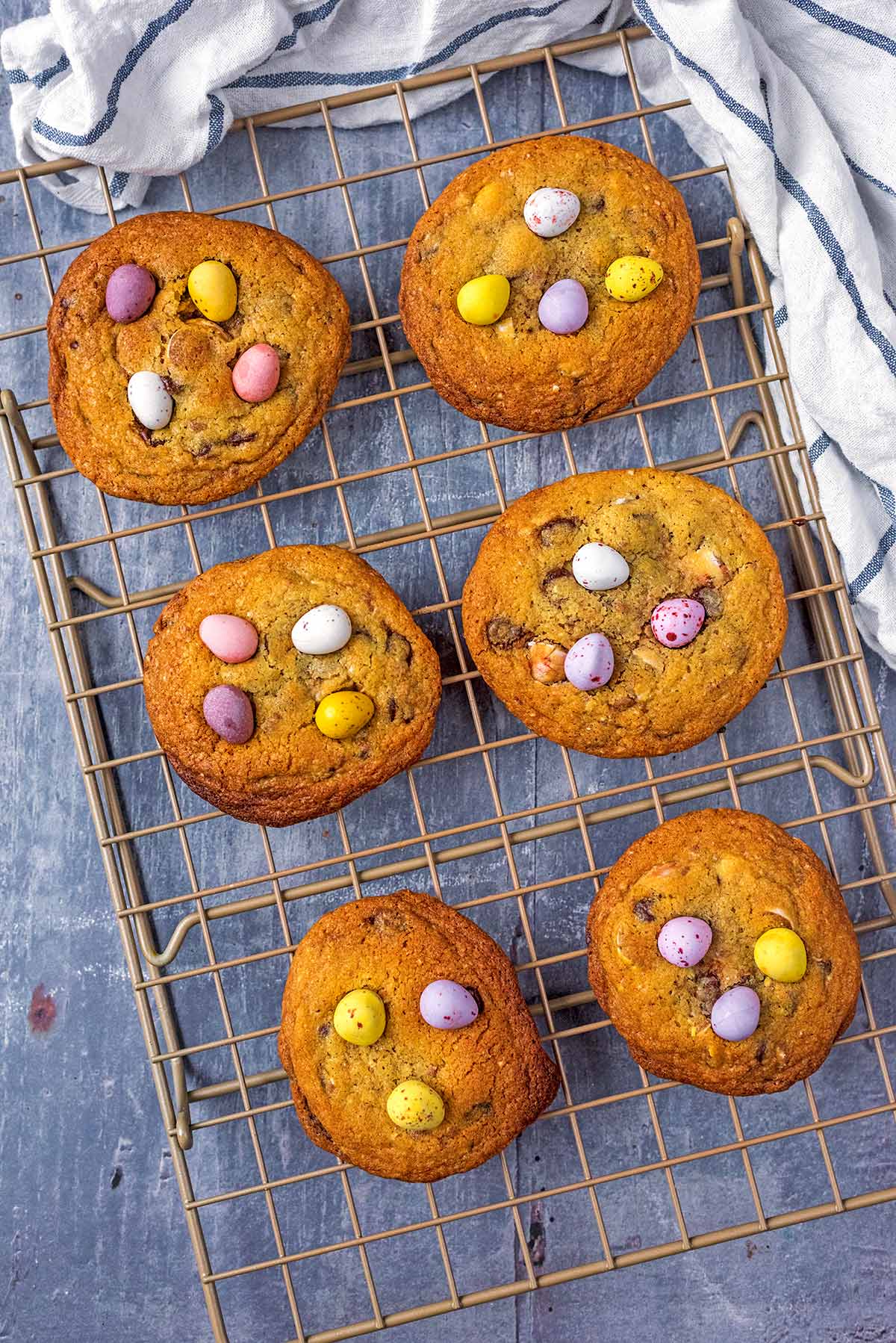 Six cookies on a wire cooling rack, each cookie has mini eggs on it.