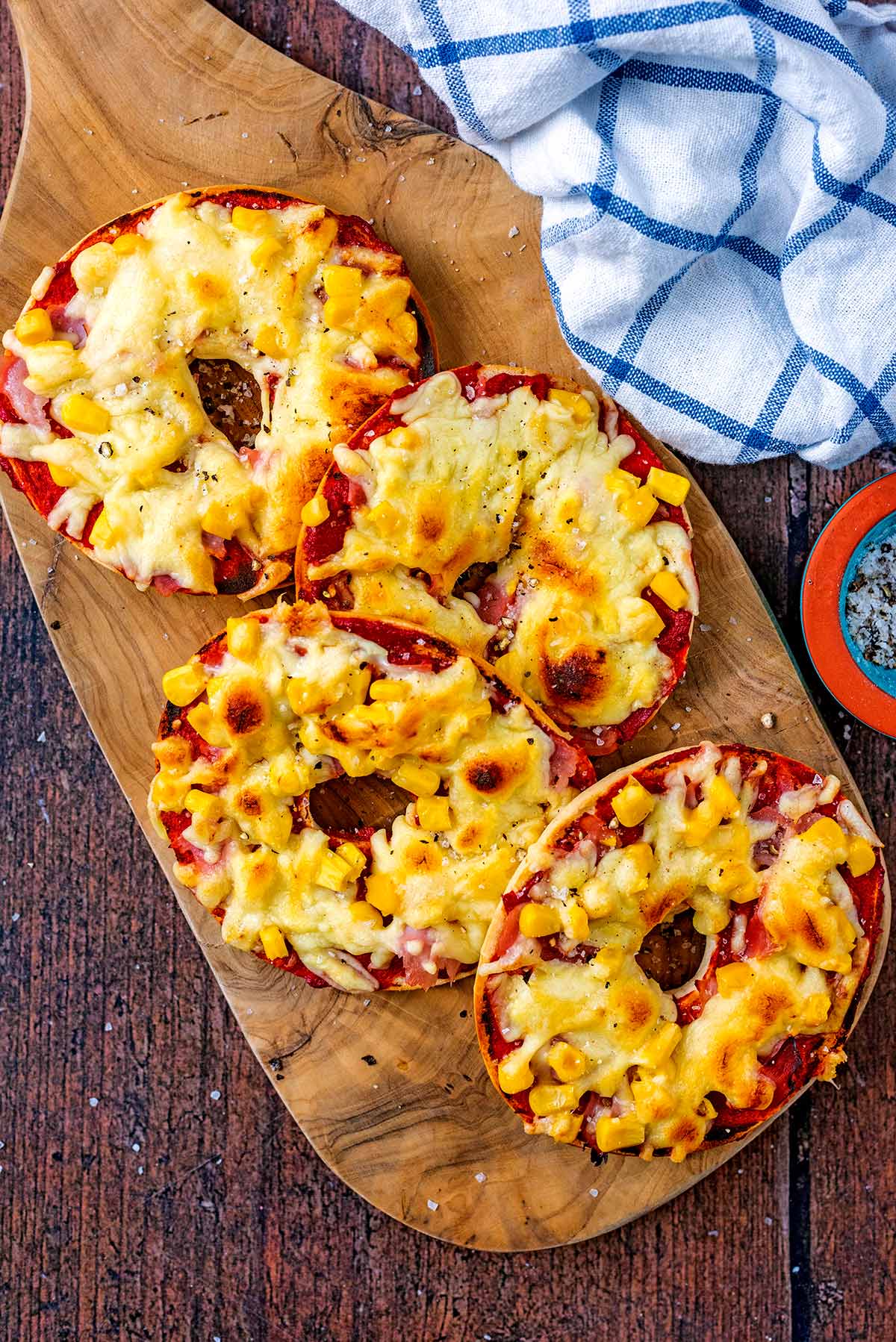 A serving board with four pizza bagels on it.