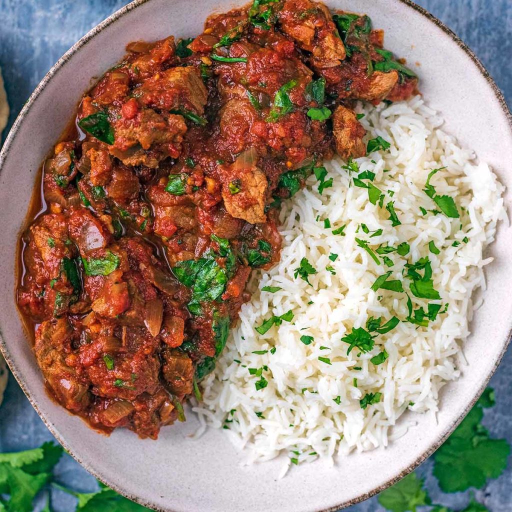 Slow cooker beef curry and rice in a round bowl.