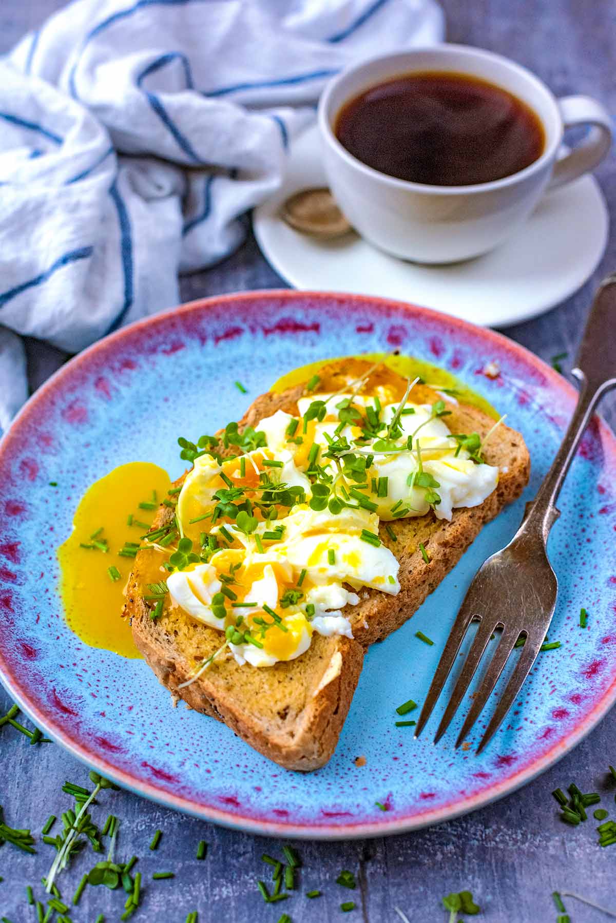 Smashed eggs on toast on a plate with a fork.
