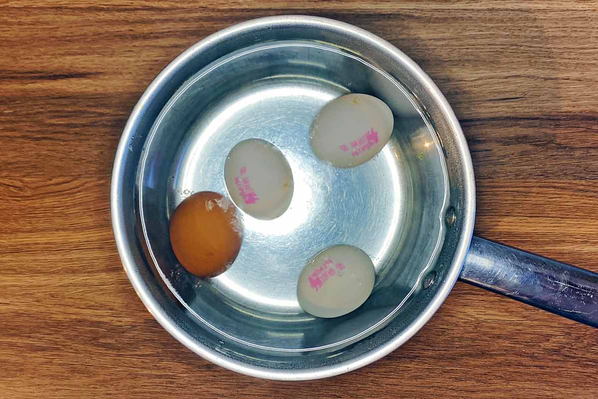 A saucepan with water and four whole eggs in it.