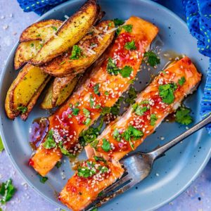 Sweet chilli salmon and potato wedges on a plate.