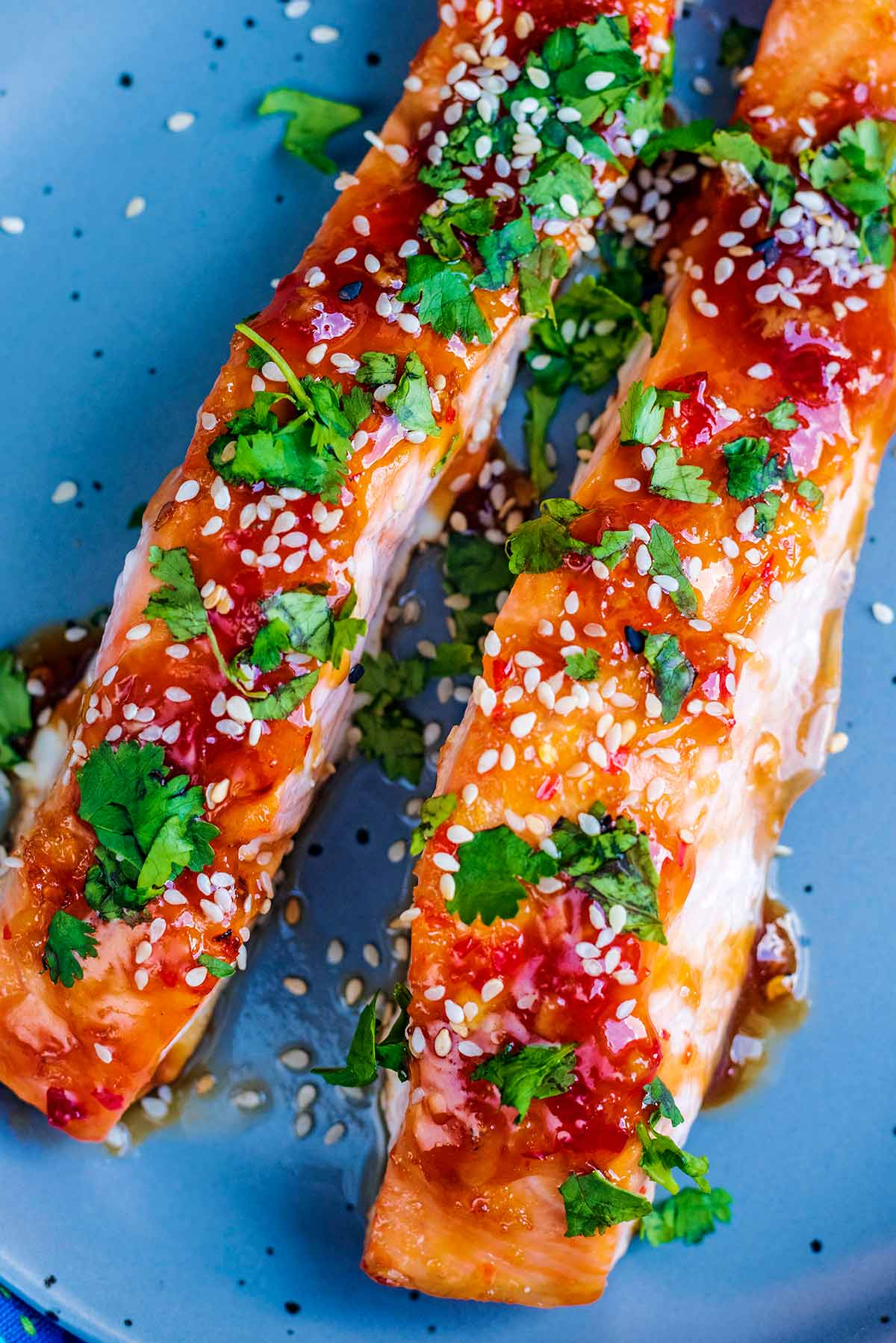 Two cooked salmon fillets topped with chopped coriander and sesame seeds.