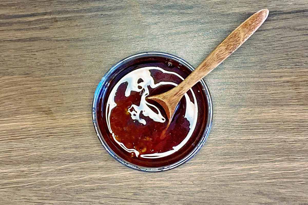 A small bowl of sweet chilli sauce and soy sauce mixed together.