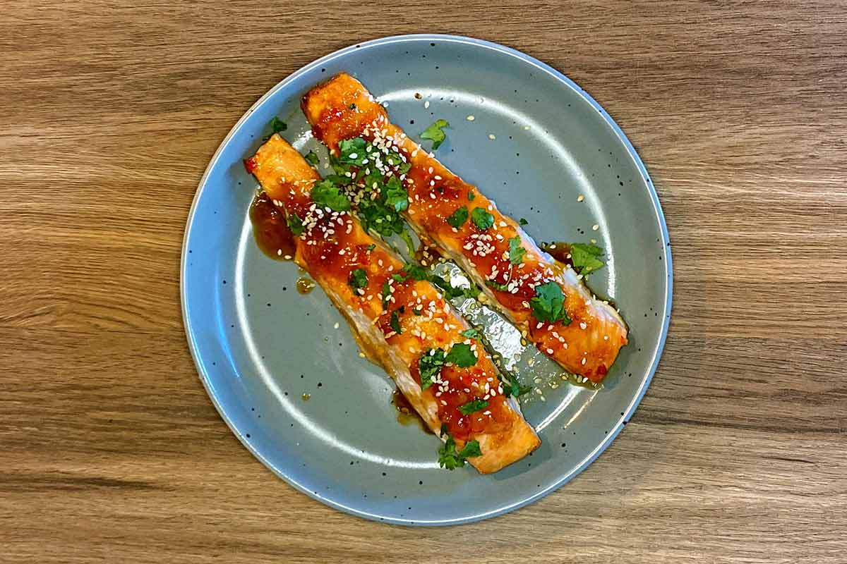 Cooked salmon fillets topped with chopped coriander and sesame seeds.