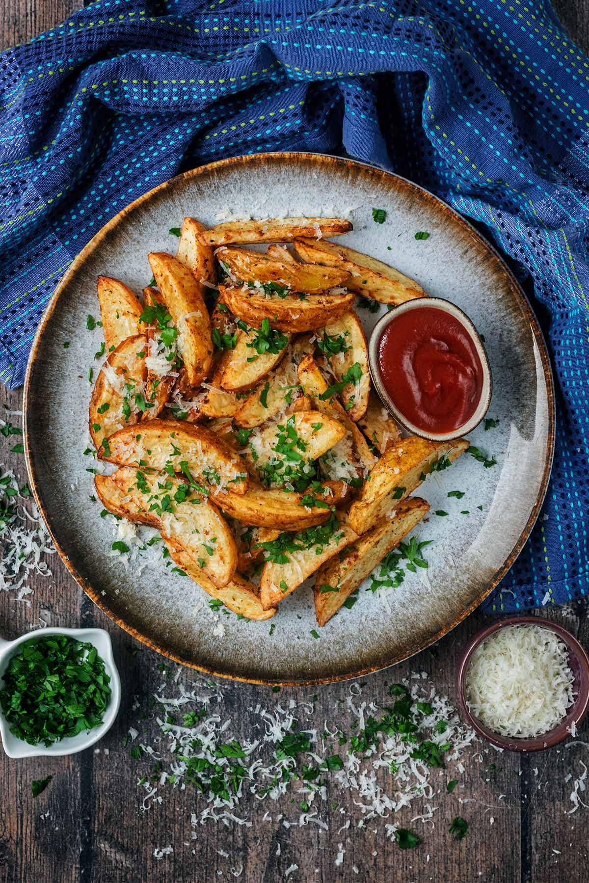 A plate of potato wedges with a small pot of ketchup.