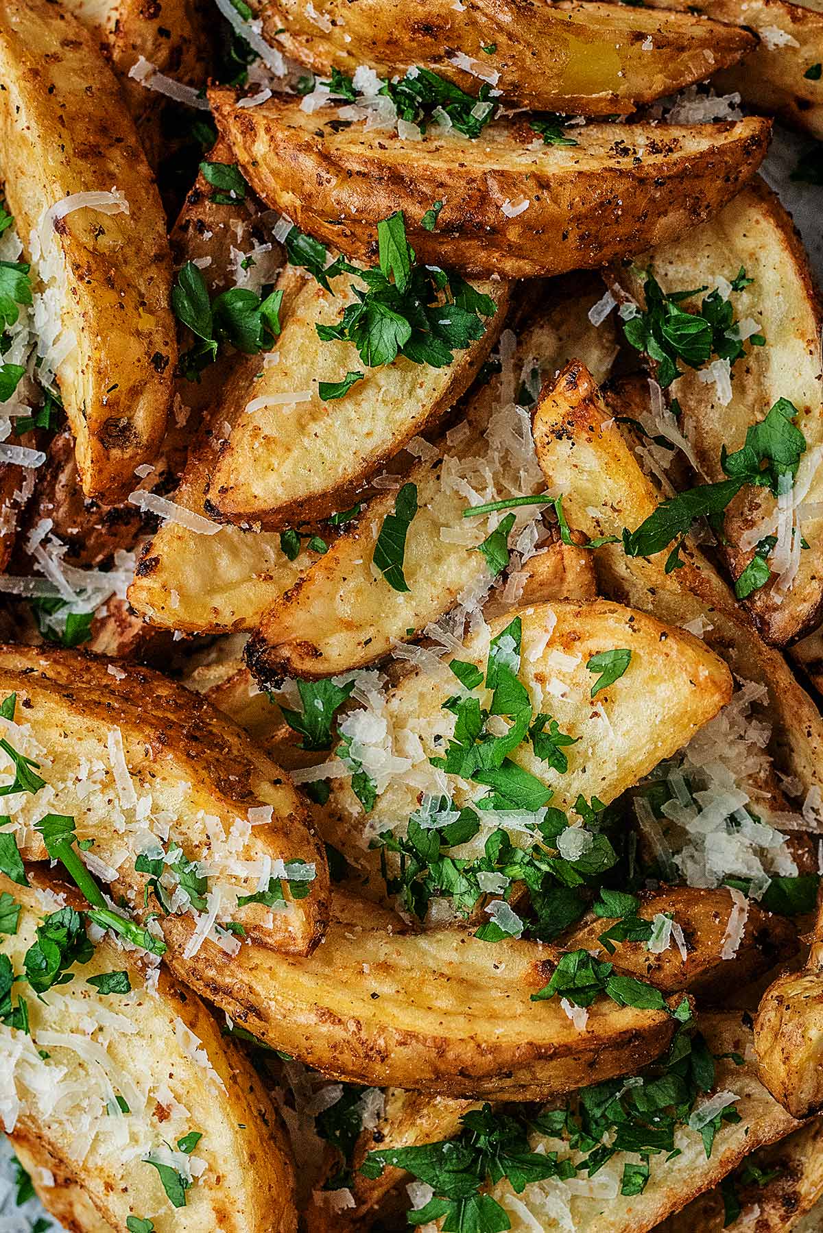 Cooked potato wedges topped with grated Parmesan and chopped parsley.