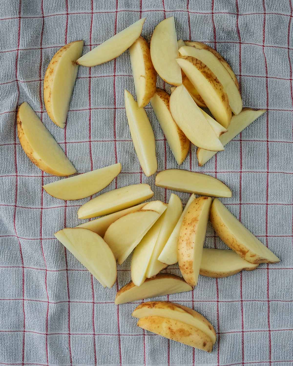 Soaked potato wedges drying on a towel.