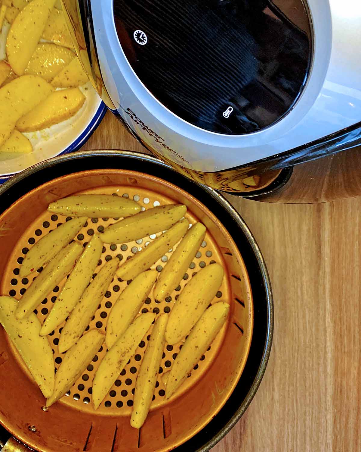 An open air fryer showing potato wedges in the basket.