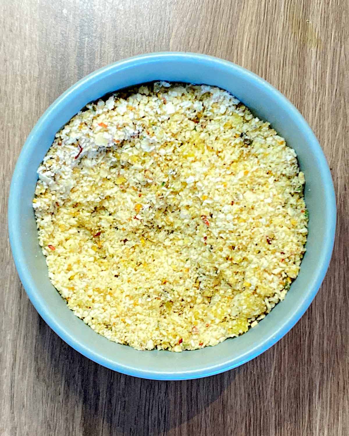 The breadcrumbs, cheese, seasoning and oil combined in the bowl.