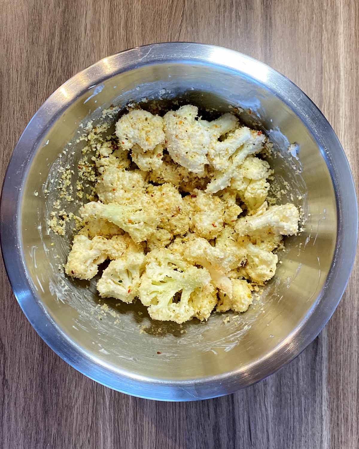 The mayonnaise cauliflower coated in the seasoned breadcrumbs in a bowl.