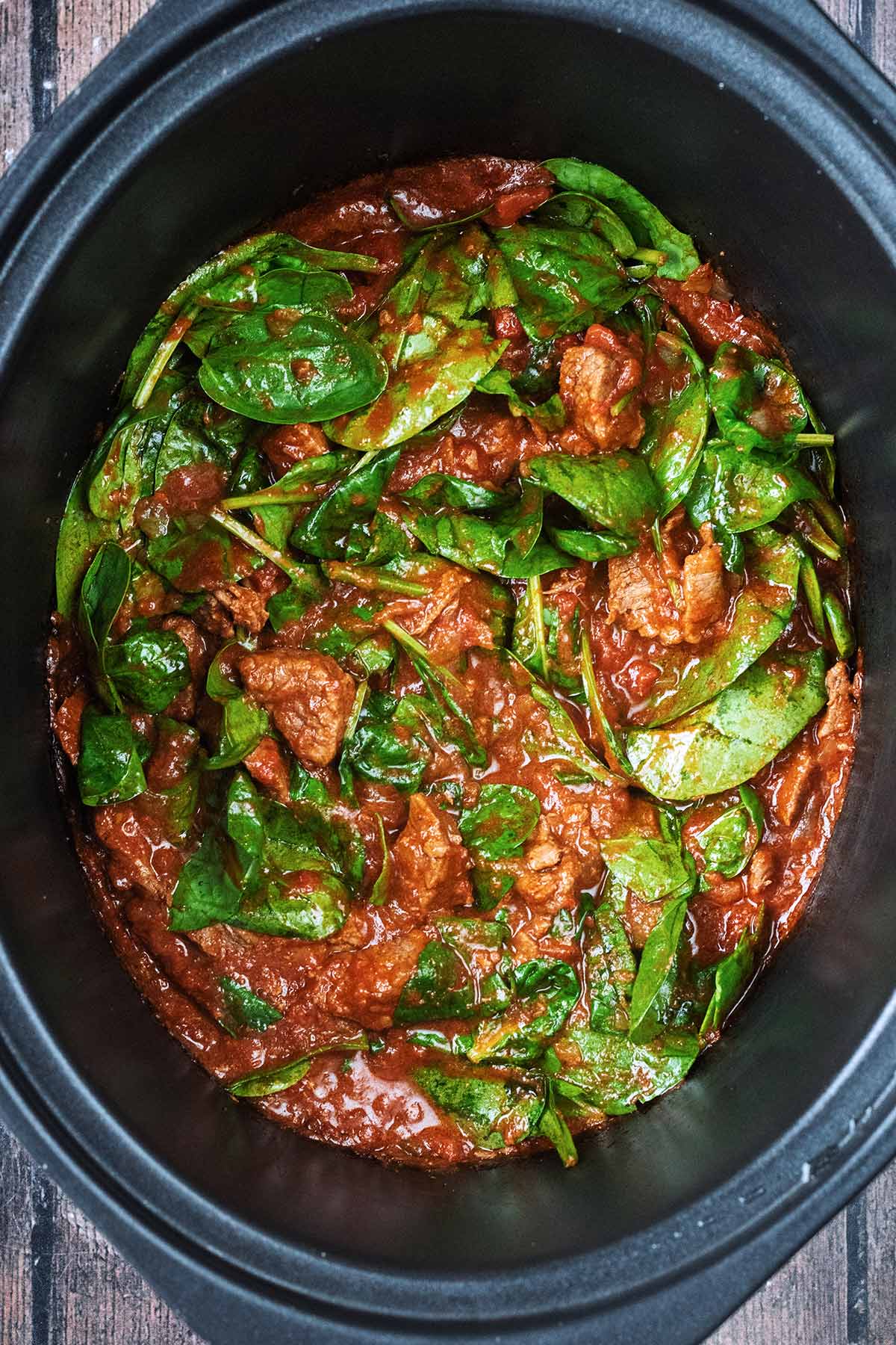 A slow cooker bowl with beef curry in it.